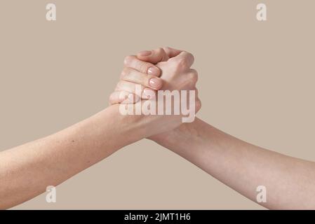 Due uomini e donne stringono la mano sul beige. Foto Stock
