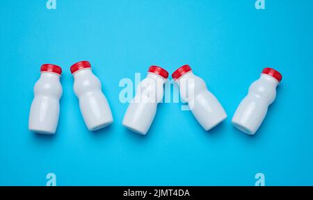 Bottiglie in plastica bianca con tappi rossi per latticini su sfondo blu, vista dall'alto Foto Stock