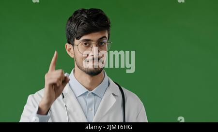 Medico arabo uomo sorridente ispanico maschio medico solleva indice dito avverte di essere attento incredulità guarda fotocamera esprimere emozione ironica Foto Stock