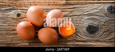 Composizione con cinque uova di pollo su un tavolo di legno. Foto Stock