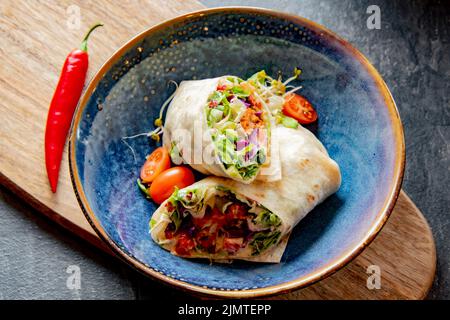 Una ciotola con due pezzi di tortilla vegetariana Foto Stock