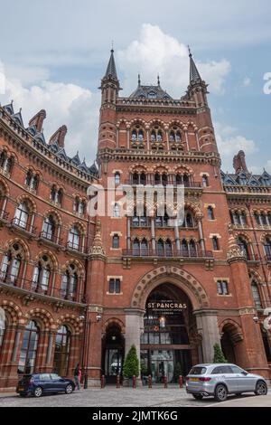 Londra, Gran Bretagna - 3 luglio 2022: Torre d'ingresso centrale su mattoni rossi storico St. Pancras Renaissance Hotel facciata sotto blu paesaggio con auto Foto Stock