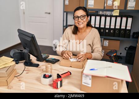 Medio età ispanica donna ecommerce business worker preparare il pacchetto in ufficio Foto Stock