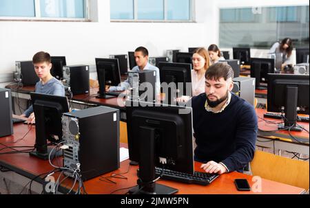 Gruppo di persone che imparano a utilizzare i computer in classe Foto Stock