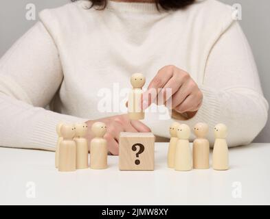 La donna mantiene la statuetta rossa di legno separata dal gruppo. Concetto di crescita della carriera, persona unica. Foto Stock