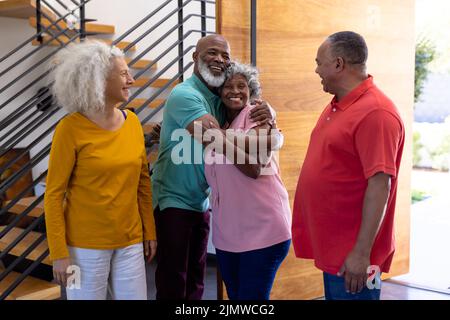 Felice anziani multirazziale che accolgono gli amici mentre in piedi alla porta in casa di pensionamento Foto Stock