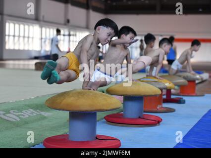 FUYANG, CINA - 7 AGOSTO 2022 - la ginnastica per i bambini si muove nella palestra del Fuyang Vocational and Technical College nell'Anhui della Cina orientale Foto Stock