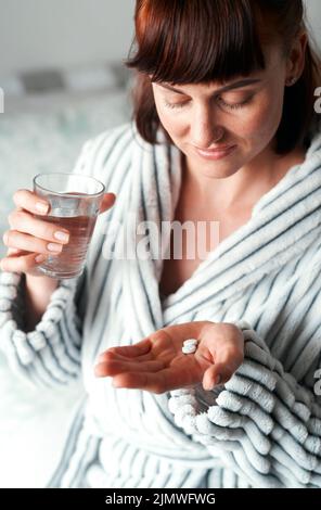 Indovino che li deve prendere appena questi... una giovane donna attraente che prende il suo farmaco nella sua camera da letto a casa. Foto Stock