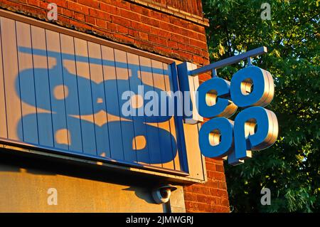 Sunset gettando un'ombra dal cartello Coop, al 156 Knutsford Road, Grappenhall, Warrington, Cheshire, Inghilterra, REGNO UNITO Foto Stock