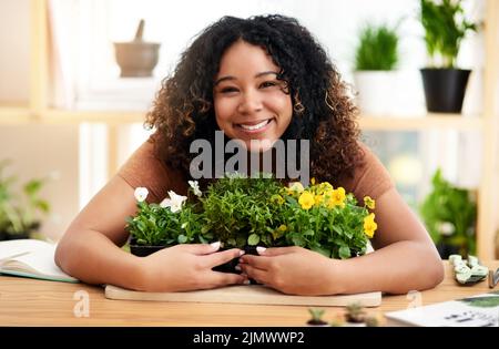 Questi sono il mio orgoglio e la mia gioia. Ritratto corto di una giovane botanista femminile attraente che lavora nel suo fiorista. Foto Stock
