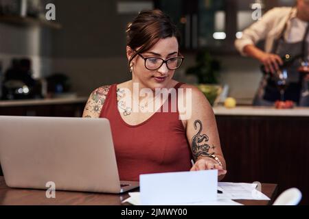 Va bene il prossimo. Una giovane ragazza allegra che lavora su un notebook e fa lavoro di documentazione mentre è seduto a un tavolo a casa. Foto Stock