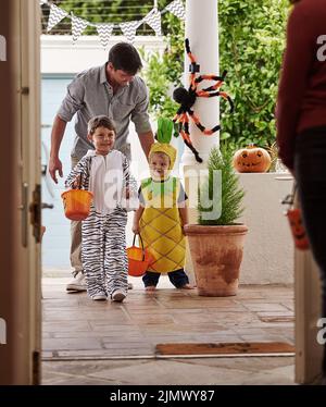 Halloween è sempre un vero piacere. Sparo a tutta lunghezza di un padre e dei suoi adorabili figli giovani trick o trattando insieme su Halloween. Foto Stock