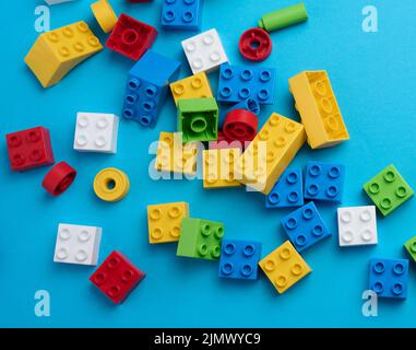 Parti sparse di un progettista di plastica per bambini, vista dall'alto. Sfondo giallo blu Foto Stock