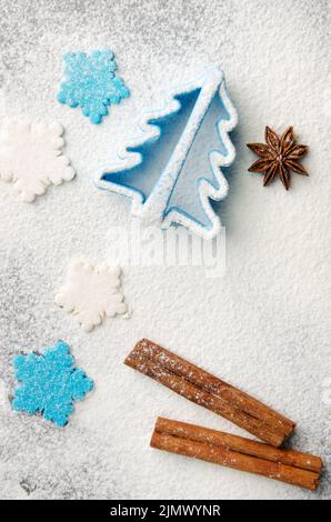 Sfondo della cucina di Natale fatto di farina, bastoncini di cannella, anice, taglierina biscotto e spolverini di zucchero Foto Stock