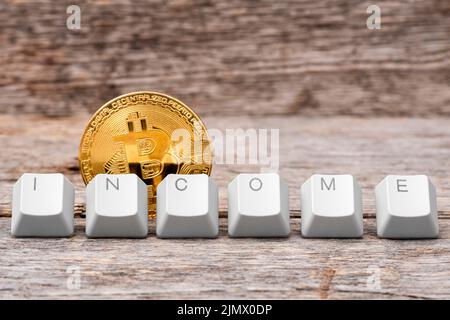Bitcoin moneta e tastiera del computer tasti disposti per incantare parola DI REDDITO Foto Stock