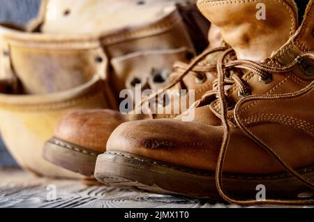 Giallo cuoio utilizzato stivali da lavoro e cinghia attrezzo su sfondo di legno closeup. Posto per il testo Foto Stock