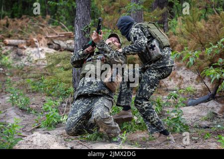 I membri delle forze di difesa territoriale di Bucha detengono le loro posizioni mentre prendono parte alla formazione di combattimento nella foresta di Bucha. Formazione dell'unità di difesa territoriale della città di Bucha. Le truppe russe il 24 febbraio 2022 entrarono in territorio ucraino, avviando un conflitto che ha provocato distruzione e una crisi umanitaria. Foto Stock