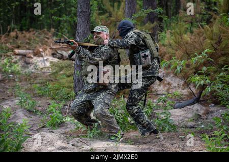 I membri delle forze di difesa territoriale di Bucha detengono le loro posizioni mentre prendono parte alla formazione di combattimento nella foresta di Bucha. Formazione dell'unità di difesa territoriale della città di Bucha. Le truppe russe il 24 febbraio 2022 entrarono in territorio ucraino, avviando un conflitto che ha provocato distruzione e una crisi umanitaria. Foto Stock