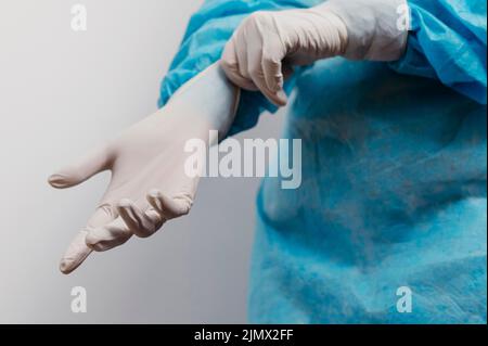 Giovane medico che indossa guanti chirurgici Foto Stock