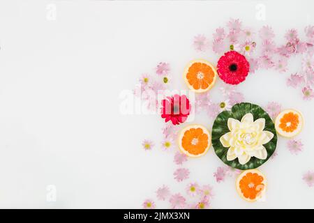 Bagno con vista ad angolo alto latte decorato con fettine di pompelmo vari fiori Foto Stock