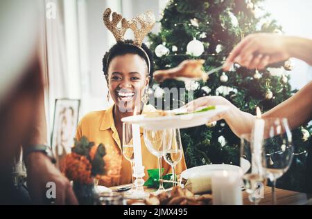 I pranzi di Christmases sono la mia cosa favorita mai. Una giovane donna attraente sorridente mentre fa il pranzo di Natale con i suoi amici a casa. Foto Stock
