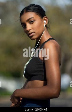 Shes un corridore della città. Ritratto di una giovane donna sportiva che ascolta musica mentre si esercita all'aperto. Foto Stock