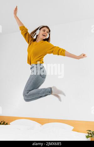 Donna che salta con le cuffie Foto Stock