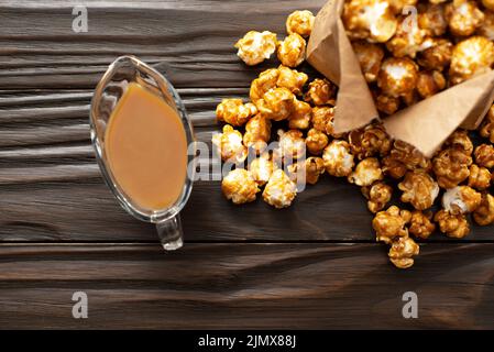 Popcorn caramellato in sacchetto di carta su tavolo da cucina in legno piatto Foto Stock