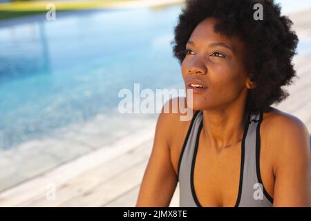 Giovane afroamericana che guarda via mentre si esercita a bordo piscina Foto Stock