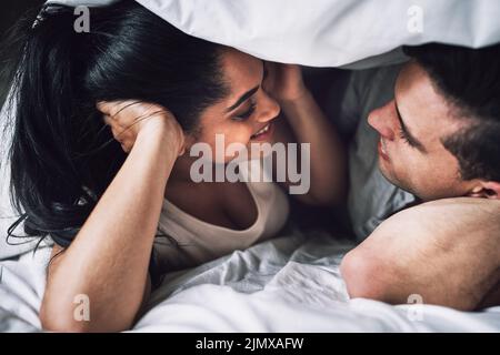 Sotto le coperte c'è la magia: Una coppia affettuosa che si trova a letto. Foto Stock