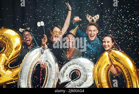 Partiremo come se non domani. Ritratto ritagliato di un gruppo di amici diversi in piedi insieme e celebrare Capodanno in un Foto Stock
