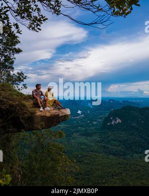 Dragon Crest montagna Krabi Thailandia, un giovane viaggiatore siede su una roccia che sovrasta l'abisso, con un bellissimo paesaggio. Trascinare Foto Stock