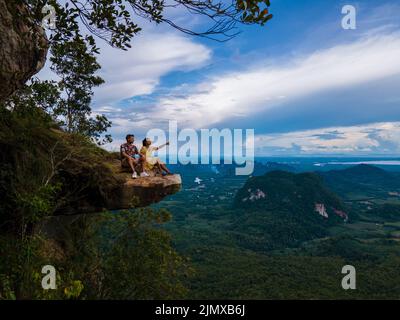 Dragon Crest montagna Krabi Thailandia, un giovane viaggiatore siede su una roccia che sovrasta l'abisso, con un bellissimo paesaggio. Trascinare Foto Stock
