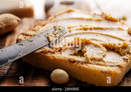 Panino con burro di arachidi e vista a basso angolo sul tagliere con i toast a parte. Concetto di alimentazione sana Foto Stock