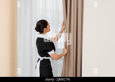 Giovane bella cameriera in uniforme utilizzando un aspirapolvere per pulire  i tappeti all suite hotel Foto stock - Alamy