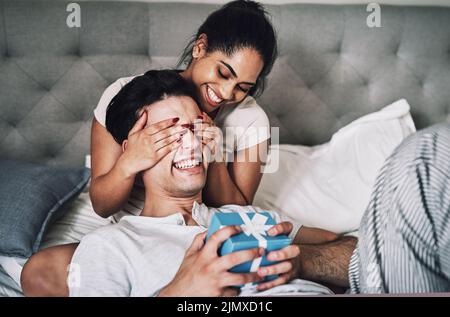 Lo ho ingannato pensando che ho dimenticato il suo compleanno. Una donna che copriva gli occhi dei suoi fidanzati e lo sorprende con un regalo. Foto Stock