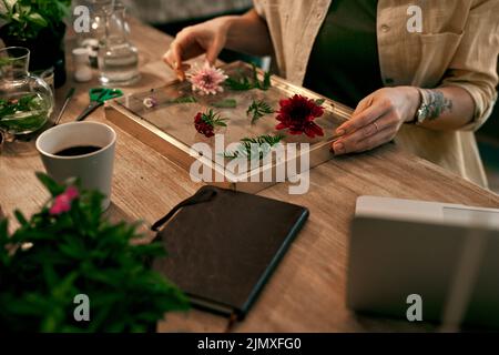 Theres nessun limite alla sua creatività. Un florist unriconoscable che decora e preme i fiori in una cornice della parete all'interno del suo deposito. Foto Stock