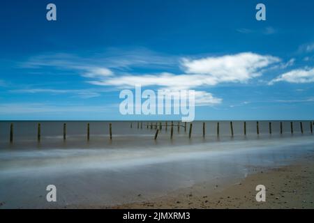 Vista a lunga esposizione di vecchie difese marine abbandonate sulla spiaggia di Happisburgh Foto Stock