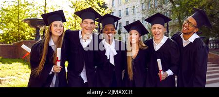 Banner con ritratto di gruppo di felice università multirazziale laureati in berretti e camici Foto Stock
