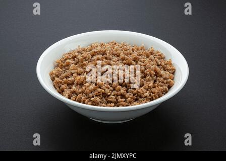 Ciotola di fiocchi di grano saraceno su sfondo nero Foto Stock