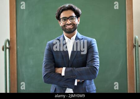 Sorridente uomo d'affari indiano che indossa un vestito in piedi in ufficio. Verticale Foto Stock