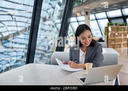 Giovane donna d'affari asiatica che utilizza videoconferenze con notebook in ufficio. Foto Stock