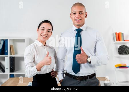 Ritratto giovane uomo d'affari sorridente businesswoman mostrando pollice su segno Foto Stock