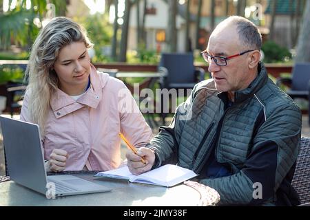 Ritratto di grave uomo di mezza età padre scrivere note, ascoltare la giovane donna, discutere informazioni in caffè. Foto Stock