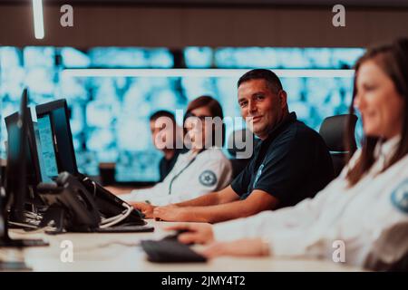 Gruppo di operatori del data center di sicurezza che lavorano in una sala di monitoraggio TVCC guardando su più monitor Officer Monitoring Multi Foto Stock