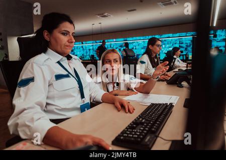 Gruppo di operatori di sicurezza femminili che lavorano in una sala di controllo del sistema dati operatori tecnici che lavorano in workstation con multipl Foto Stock