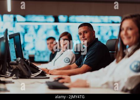 Gruppo di operatori del data center di sicurezza che lavorano in una sala di monitoraggio TVCC guardando su più monitor Officer Monitoring Multi Foto Stock