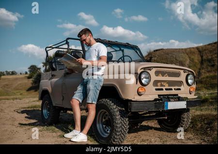 Uomo che tiene la mappa mentre viaggia in auto Foto Stock