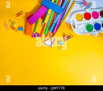 Forniture scolastiche su sfondo giallo. Vista dall'alto. Concetto di shopping online. Foto Stock