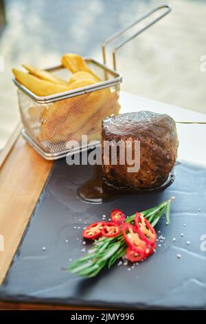 Filetto mignon alla griglia e patatine fritte su piatto di ardesia Foto Stock